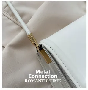 Detail van witte minimalistische schoudertas met luxe goudkleurige metalen gespen