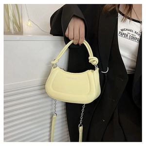 Detail of pale yellow semi-circular crossbody bag with knotted handle and silver chain