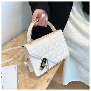 Close-up of white quilted leather handbag with gold metal twist lock and top handle