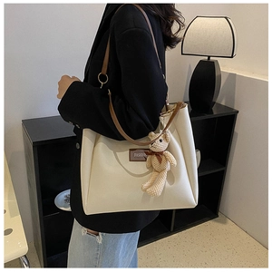 Dettaglio della borsa tote in pelle PU bianca con spalline marroni e ciondolo a orso