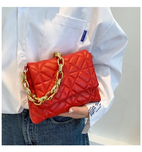 Detail of red quilted PU leather handbag with chunky gold acrylic chain and flap