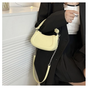 Detailed side view of yellow faux leather crescent bag with gold chain strap on model