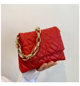 Macro view of bright red quilted leather handbag with thick gold chain handle detail