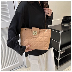 Détail d'un sac matelassé marron clair avec une boucle ronde dorée et une bandoulière chaîne