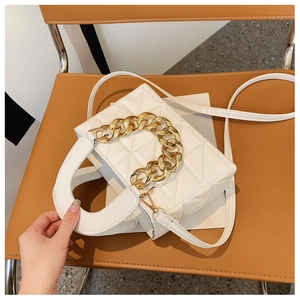 Detailed view of white quilted bag with thick gold chain handle and detachable strap