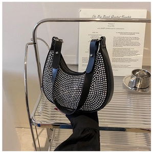 Close-up of a crescent underarm bag with shimmering silver rhinestones and black leather strap
