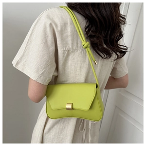 Detail of lime green baguette bag featuring smooth leather and decorative knotted strap