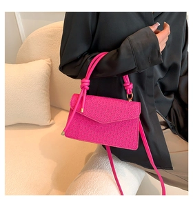 Hot pink woven handbag with a unique knotted handle and slim strap shown on a black shirt
