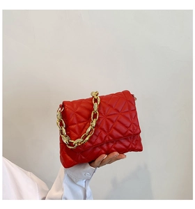Detail of red quilted PU leather shoulder bag featuring a chunky gold acrylic chain handle