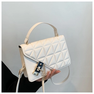 Detail of cream quilted handbag featuring geometric flap, gold chain, and metal lock buckle