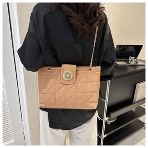 Détail du sac à bandoulière matelassé avec chaîne dorée et boucle sur une femme