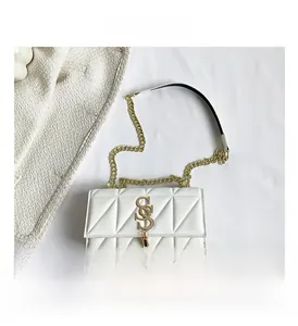 Detail of white quilted handbag with gold S-shaped logo and elegant chain strap