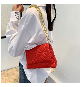 Detailed view of red puffy quilted shoulder bag with decorative thick gold chain strap