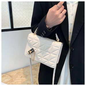 Close-up of a white quilted crossbody bag with a gold-tone lock and chain detail
