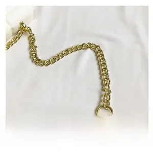 Detailed close-up of golden metal chain strap with white quilted leather stitching detail