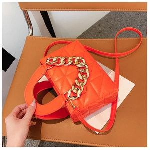 Close-up of bright orange quilted PU leather bag with chunky gold metal chain detail