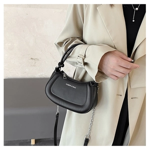 Detail of black matte crescent bag with metal chain strap and embossed fashion text