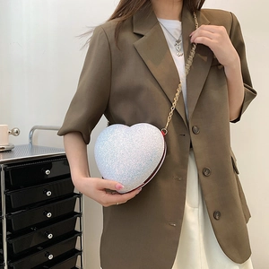 Sparkly white heart-shaped sequin crossbody bag with gold chain strap shown on model
