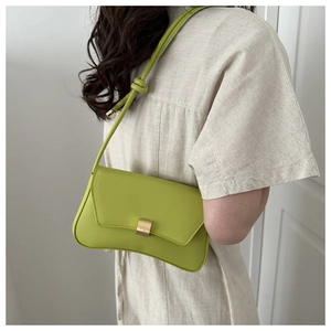 Close-up of light green shoulder bag with golden lock and knotted strap detail