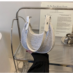 Detail shot of a white half-moon bag with silver rhinestones on a metal cart