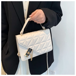 Detail of white quilted handbag featuring a unique black and gold clasp with chain trim