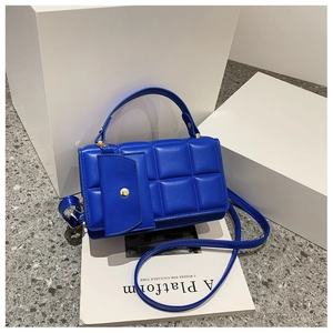Detail of bright blue quilted crossbody bag with gold rivets and matching small pouch