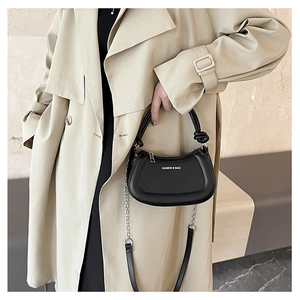 Close-up of a black half-moon bag with knotted handle and silver chain strap details