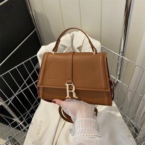 Minimalist brown leather small square bag with gold R-buckle in a metal basket