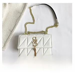 Detail of white quilted handbag featuring gold letter logo and fringe tassel with phone size ref