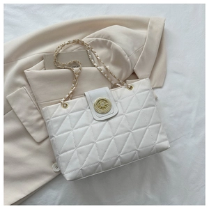 Dettaglio borsa a tracolla trapuntata beige con fibbia dorata su un blazer beige