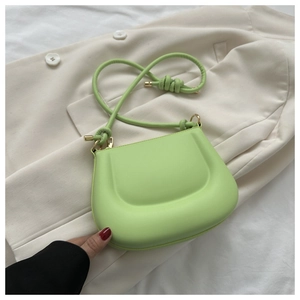 Detailed top view of light green PU leather crescent crossbody bag on beige blazer