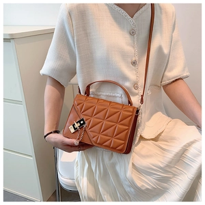 Detail of caramel brown quilted shoulder bag with geometric stitching and gold chain lock