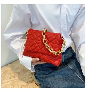Detail of red quilted PU leather shoulder bag with a bold golden acrylic chain strap