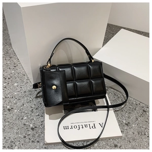 Detail of black quilted shoulder bag with gold hardware and mini coin purse attachment