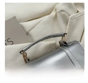Detail of silver metallic handbag showing the gold hook and comfortable round handle