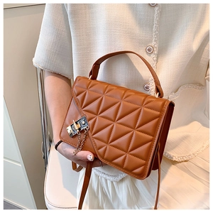 Detail of brown quilted crossbody bag with triangle stitching and metal gold lock