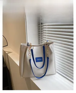 Close-up of blue leather strap with gold chain on a cream white tote bag detail