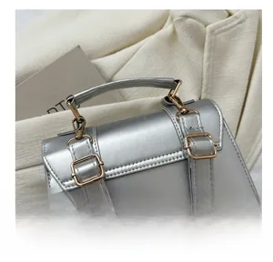 Detailed macro view of the adjustable pale gold metal buckle on silver textured backpack strap