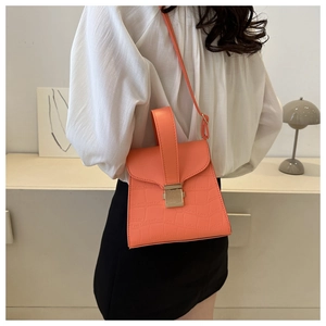 Détail d'un sac à main orange à motif crocodile avec fermoir doré et poignée élégante