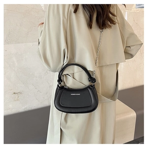 Detail of a black semi-circular crossbody bag with FASHION & BAGS text and chain strap