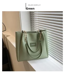 Detail of light green tote bag with metal chain strap on a minimalist windowsill