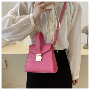 Sac à main rose à motif crocodile avec fermoir doré et bandoulière sur modèle élégant
