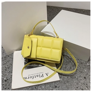 Dettaglio della borsa tote gialla trapuntata con mini pochette su pietra grigia