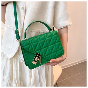 Detail of green quilted crossbody bag with golden metal lock and chain strap on a model