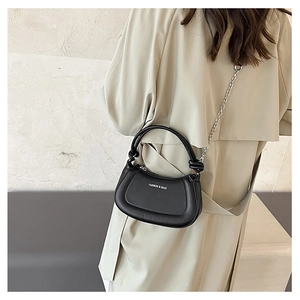 Close-up of minimalist black leather crossbody bag with silver chain and white logo