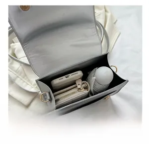 Interior storage detail of the silver rectangle bag showing phone, wallet, and umbrella