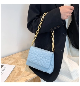 Close-up of light blue quilted crossbody bag with gold chunky chain strap and PU texture