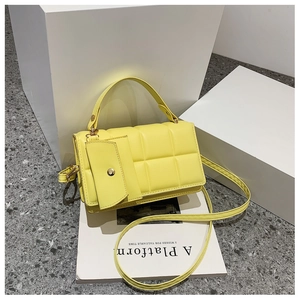 Detail of yellow quilted square tote bag with mini pouch and gold hardware accents