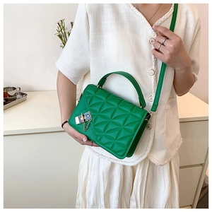 Close-up of green quilted leather handbag featuring a gold twist lock and chain detail