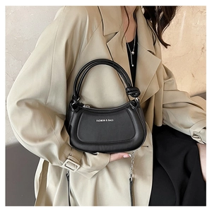 Chic black half-moon leather handbag with knot detail and silver chain on trench coat model